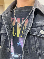 Silver-tone chain necklace with small pendant on denim jacket and graphic T-shirt