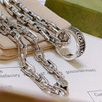 Layered silver-tone chain necklace with round medallion charm and oval clasp