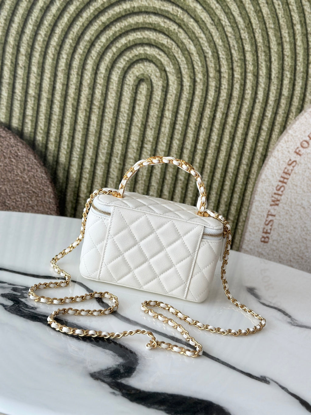 White quilted mini handbag with gold-tone chain and top handle, front view.