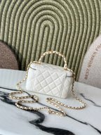 White quilted mini handbag with gold-tone chain and top handle, front view.
