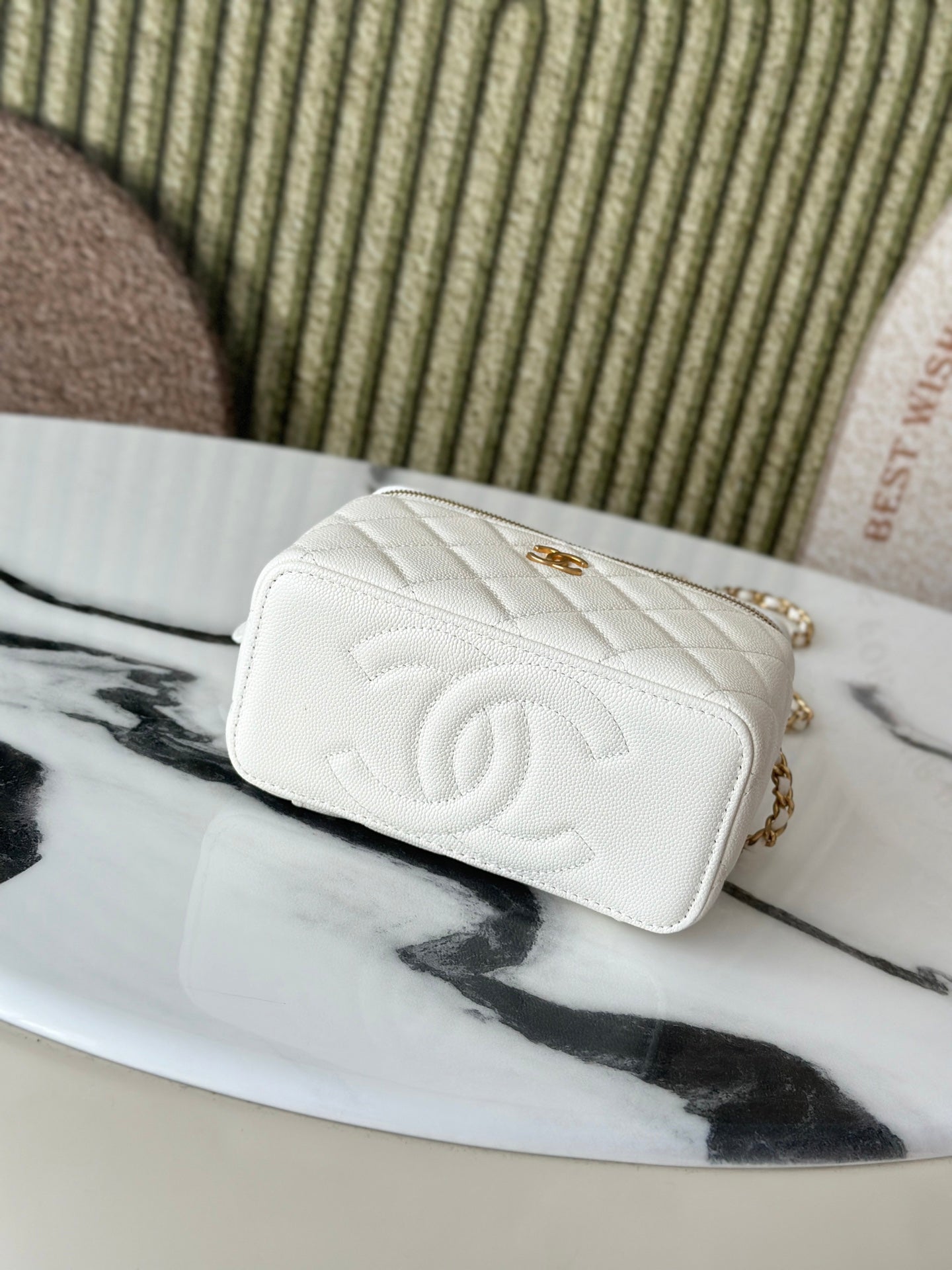 White quilted mini handbag with gold CC logo on front, flap closed.