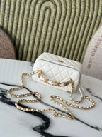 White quilted mini handbag with gold chain strap and flap closure, angled view.