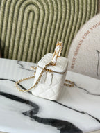 White quilted mini handbag with gold chain strap and small flap, side angle.