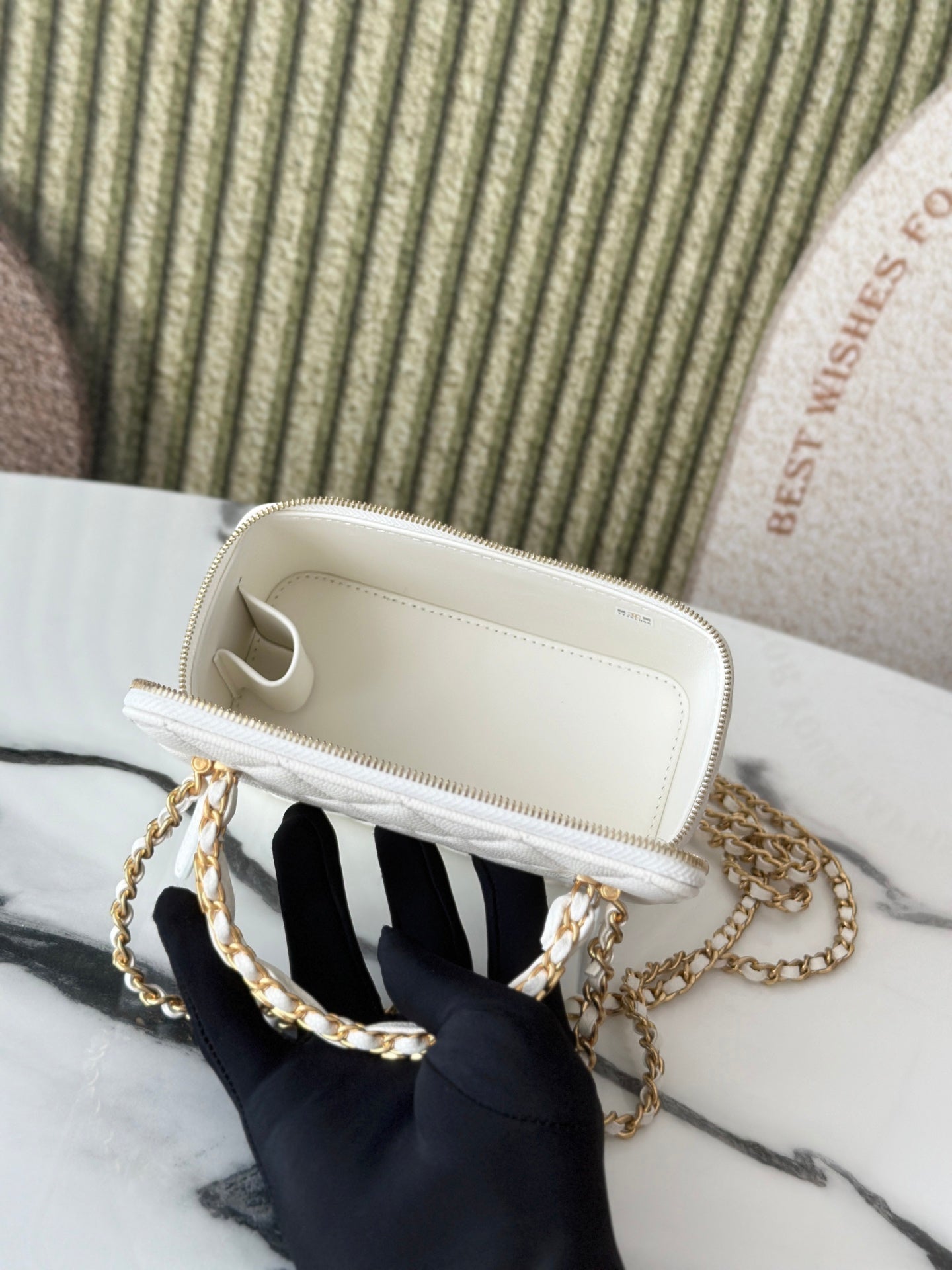 White mini handbag interior view with cream lining and gold zipper trim.