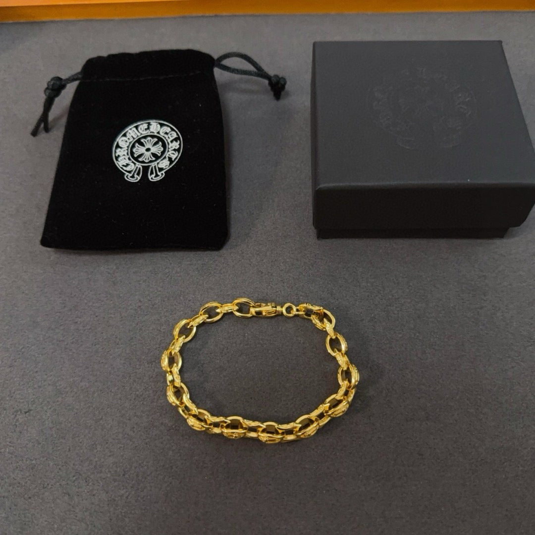 Gold chain bracelet on a gray surface with a black pouch nearby