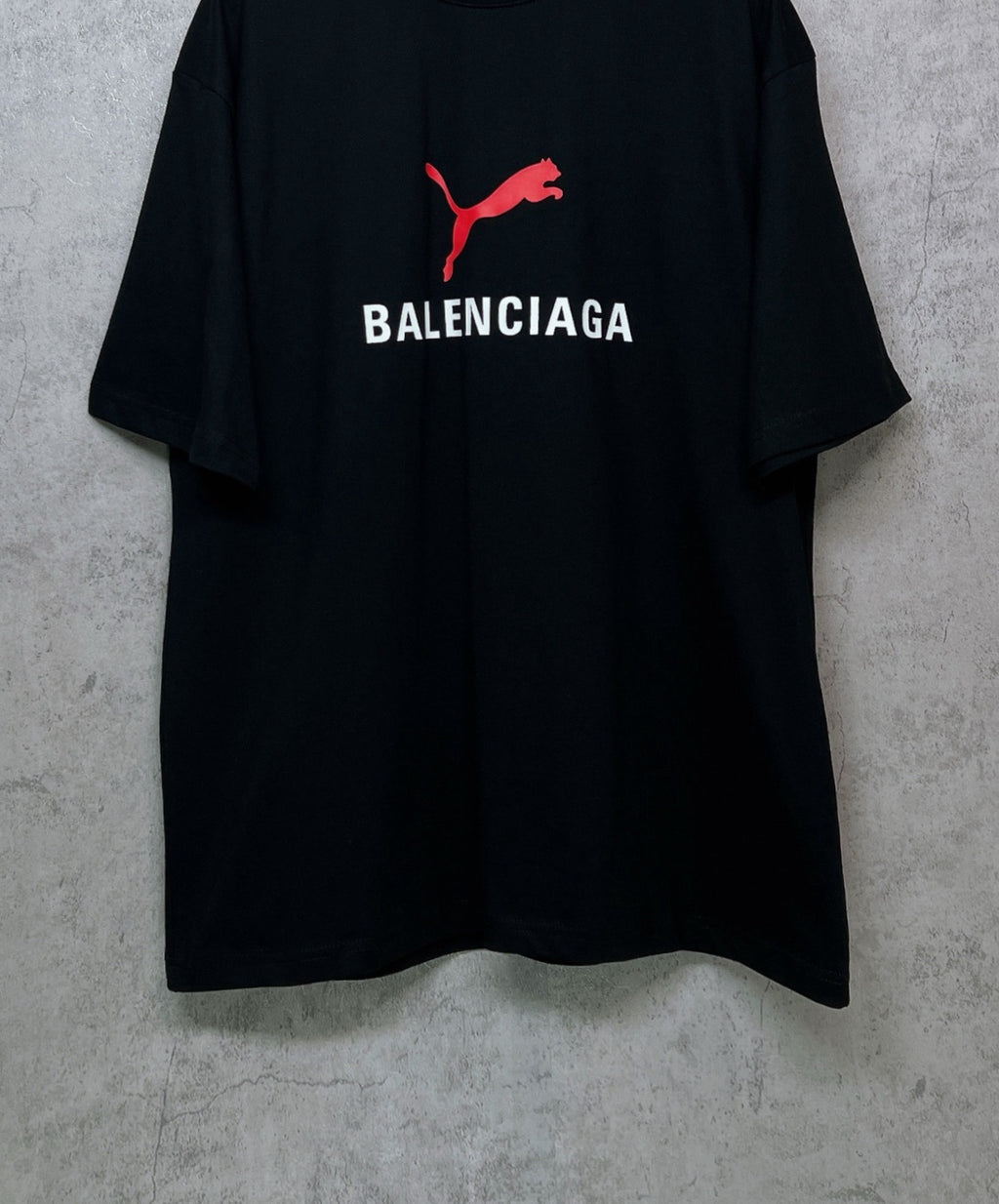 Black short-sleeve T-shirt with red puma logo above BALENCIAGA text