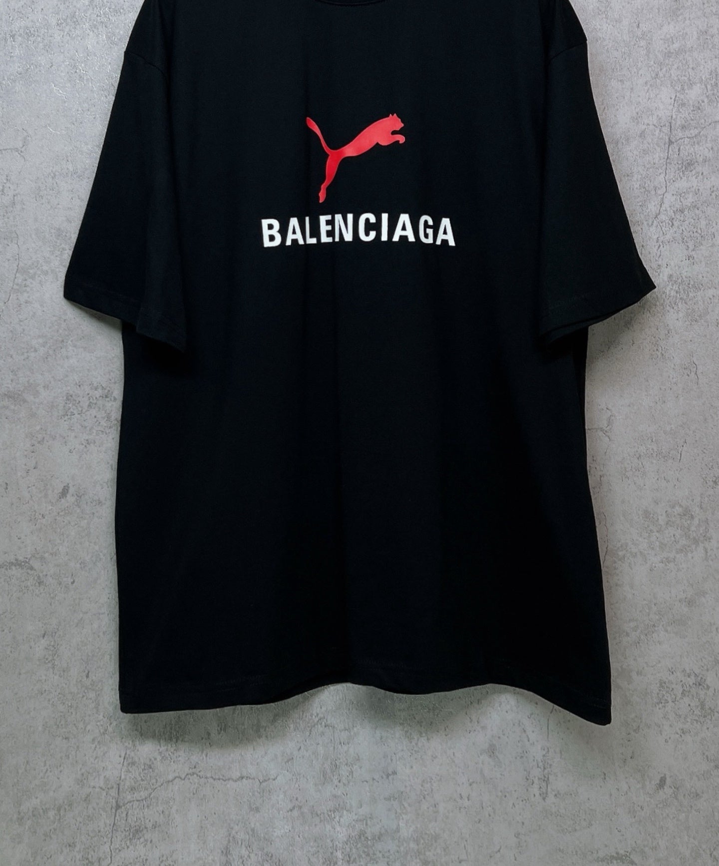 Black short-sleeve T-shirt with red puma logo above BALENCIAGA text