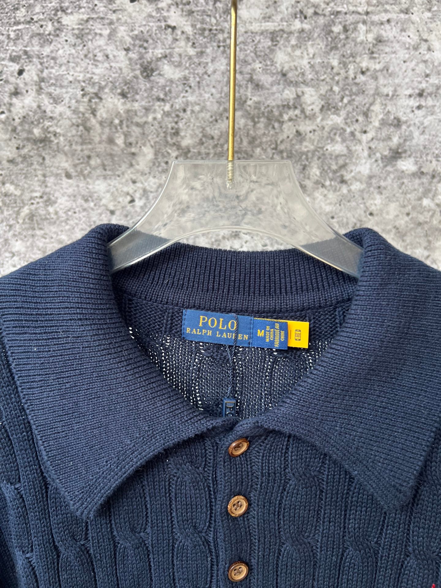 Navy ribbed polo sweater neckline with button placket and brand tag