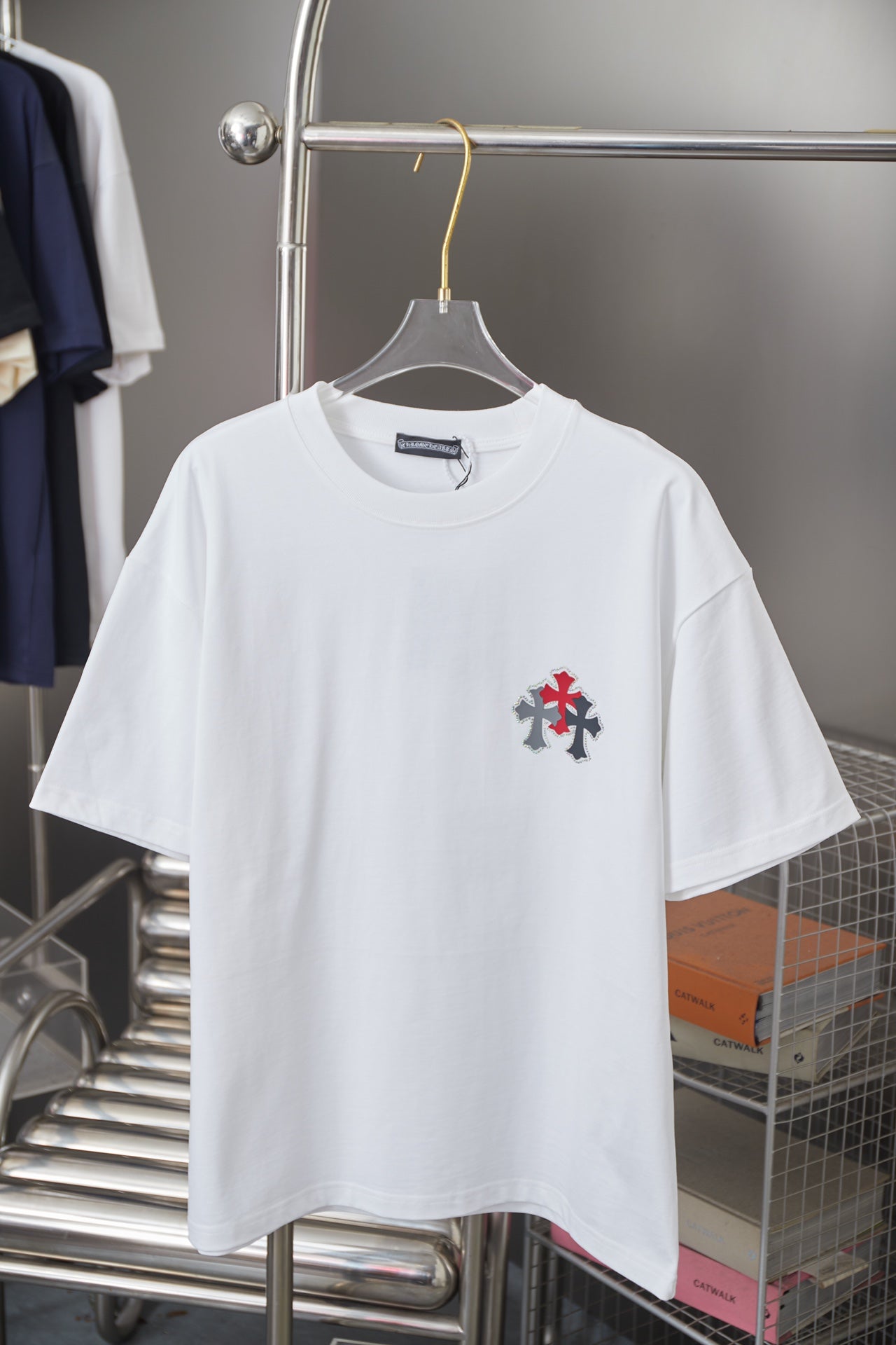 White crewneck short-sleeve T-shirt with small red-and-black cross emblem on chest