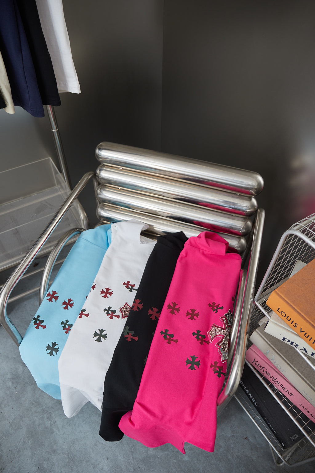Folded T-shirts in black, white, light blue, and fuchsia with red cross prints