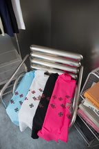 Folded T-shirts in black, white, light blue, and fuchsia with red cross prints