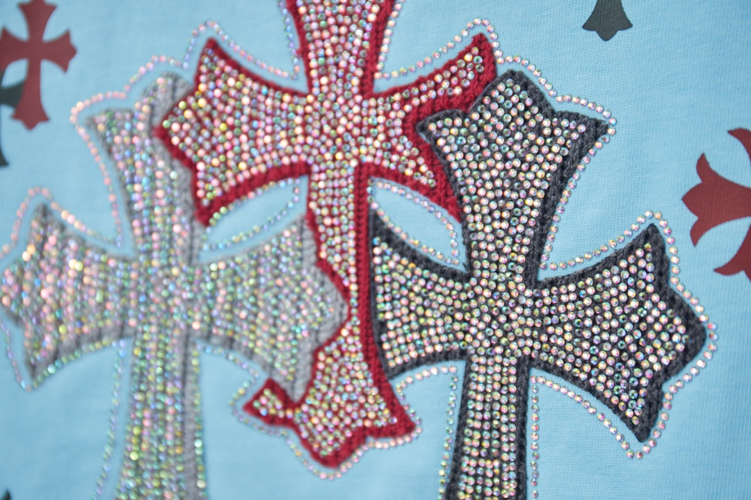 Rhinestone cross graphic with red, blue, and black accents on light blue T-shirt