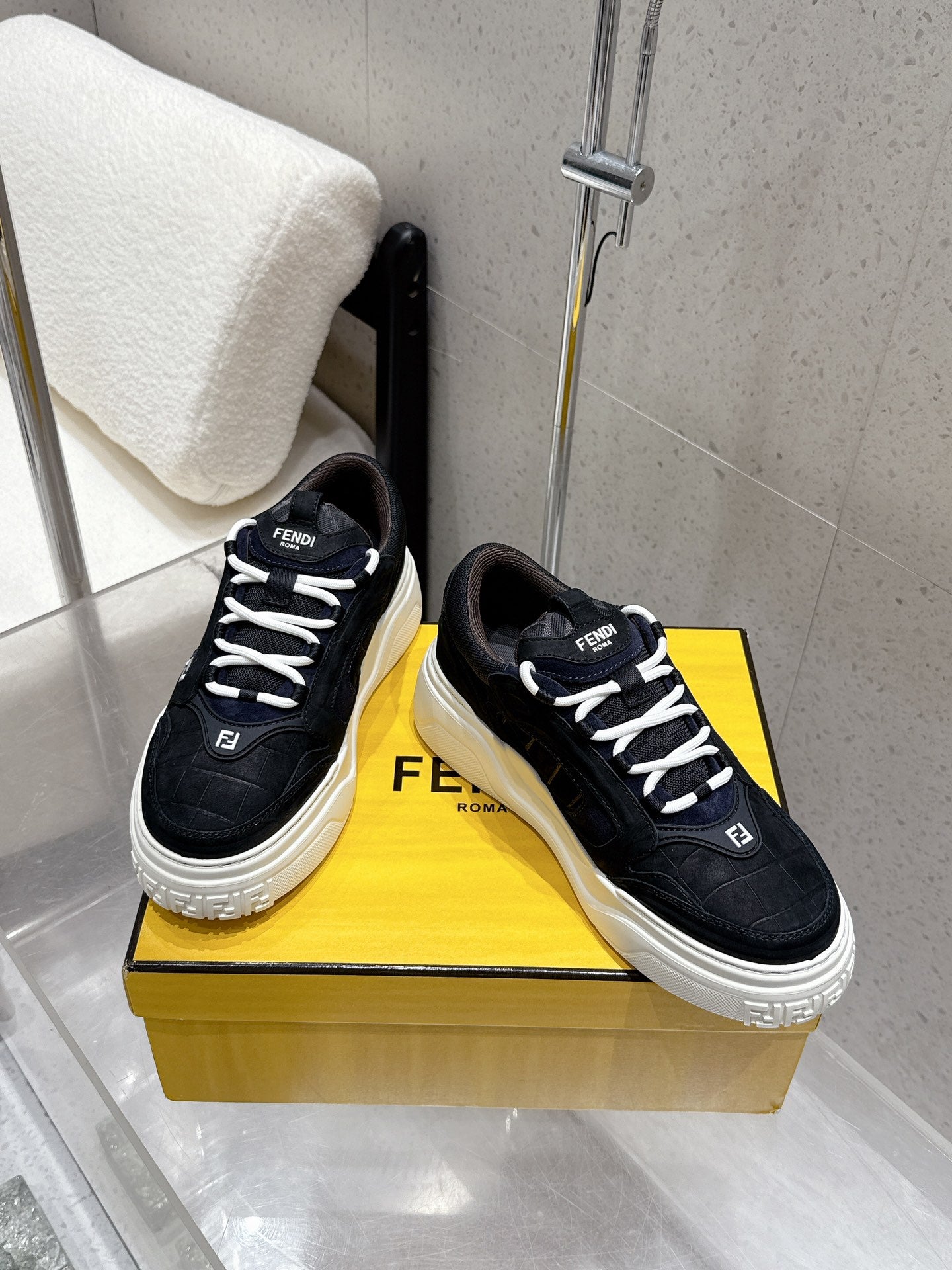 Black Fendi lace-up sneakers on box, logo tongue and textured upper.