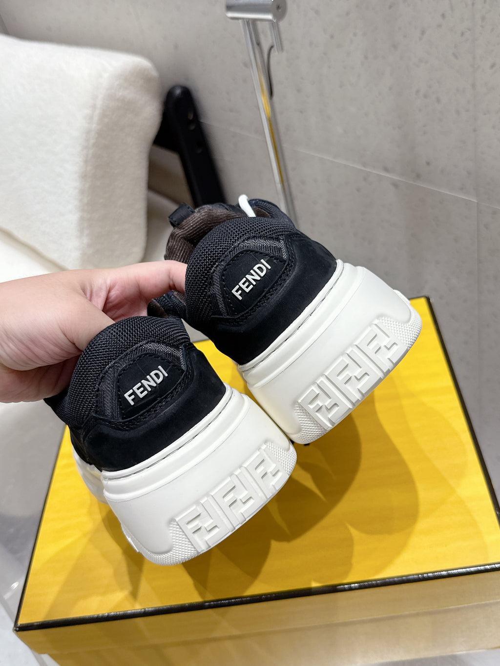 Black Fendi sneakers close-up, heel logos and white platform midsoles.