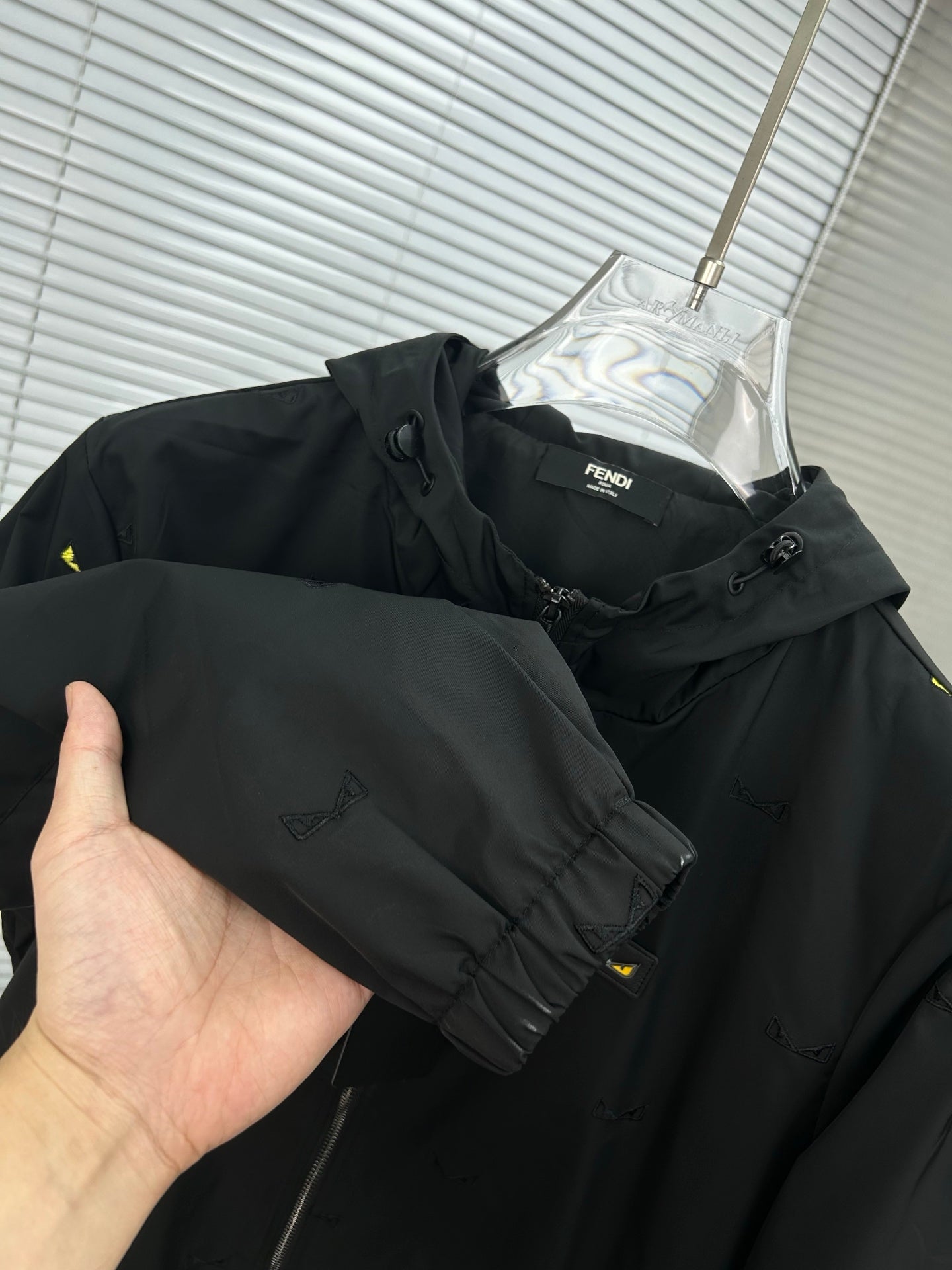 Long jacket held by hand, black hood and sleeve with yellow mini prints