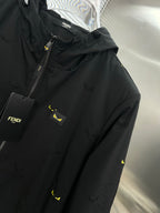 Long jacket close-up: black chest panel with logo patch, front zipper, yellow prints
