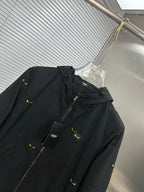 Long jacket close-up: black hood with drawstring, front zipper, yellow mini print