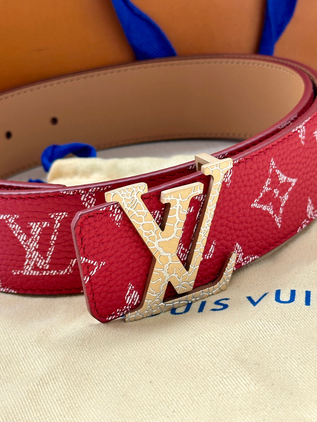 Louis Vuitton belt close-up: red monogram strap with gold LV buckle