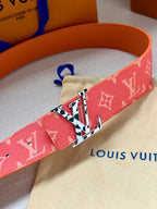 Red monogram belt detail with metal buckle and colorful geometric center plate.