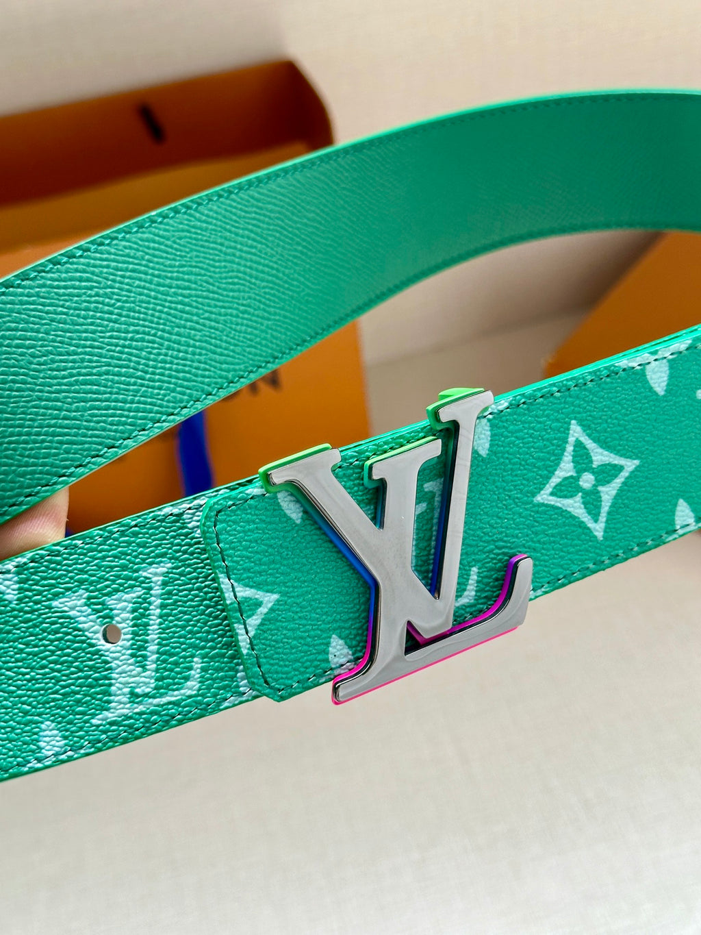 Green Louis Vuitton belt with white monogram print and silver-tone LV buckle close-up