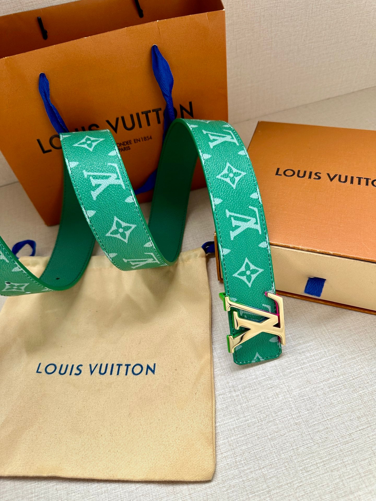 Green Louis Vuitton belt with white monogram and gold-tone LV buckle, holes visible