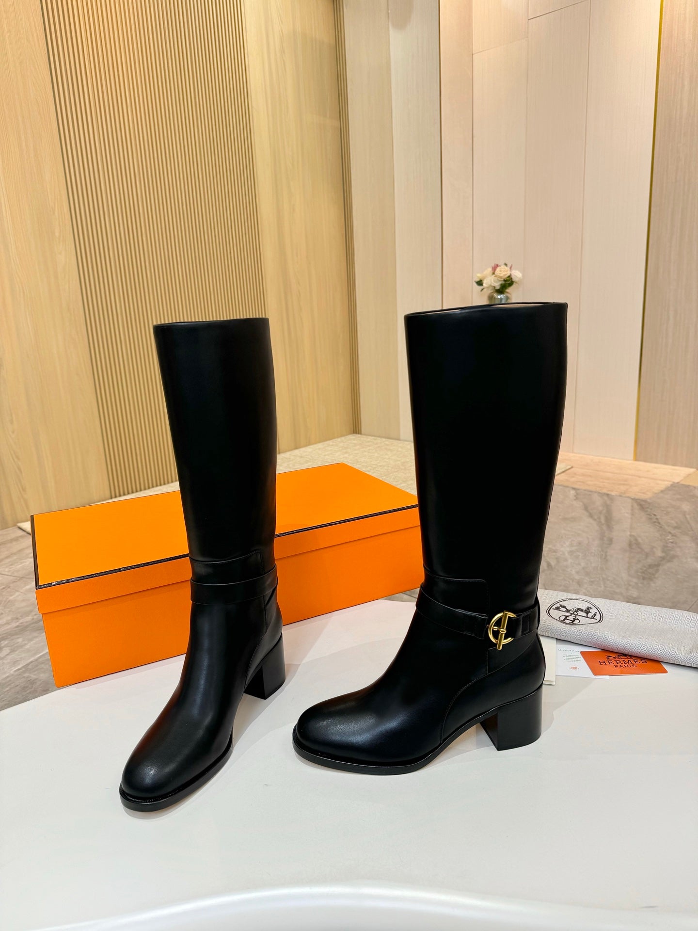 Black leather tall boots with gold logo buckle and low block heel