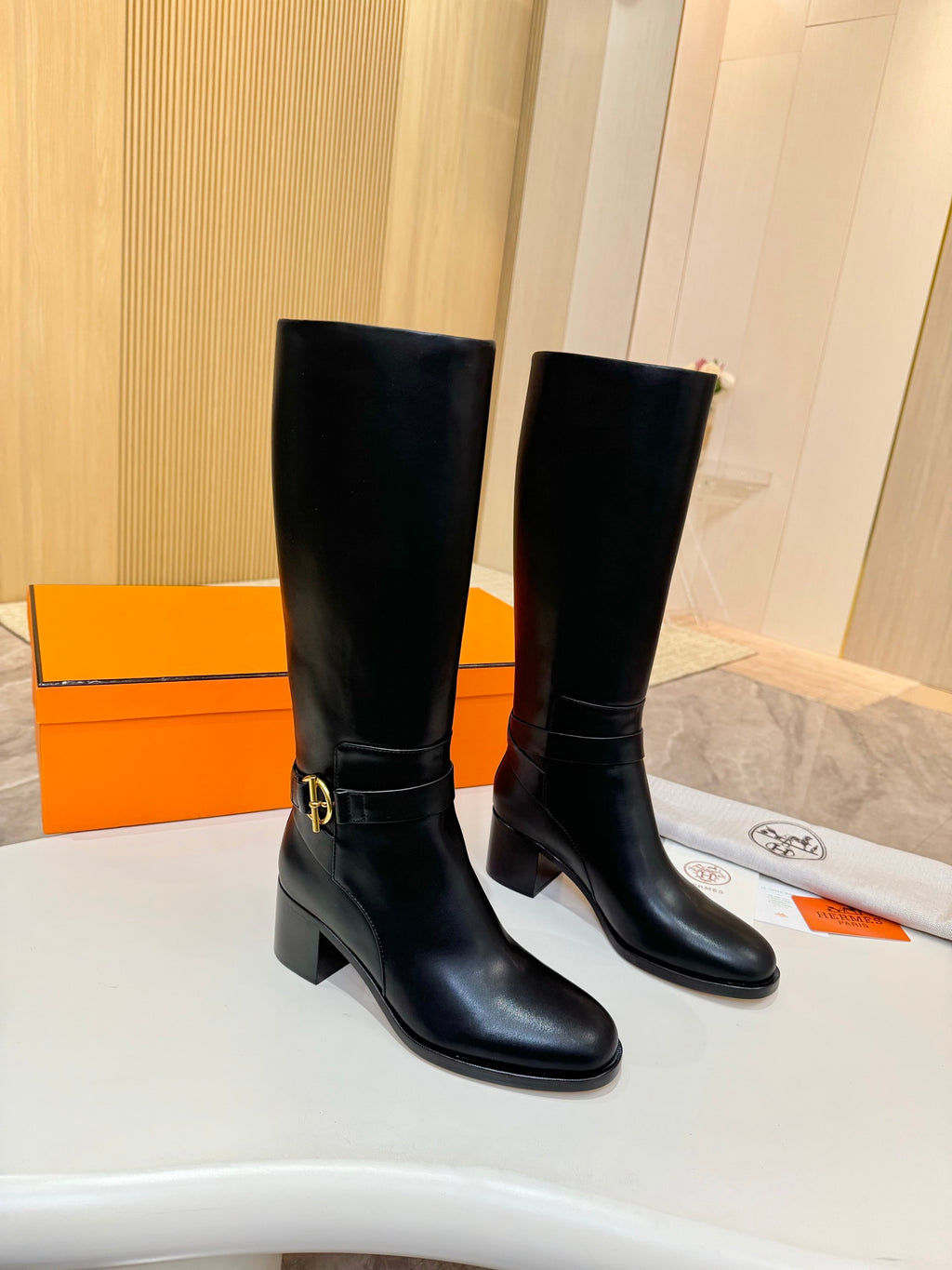 Black leather mid-calf boots with gold logo buckle, side view