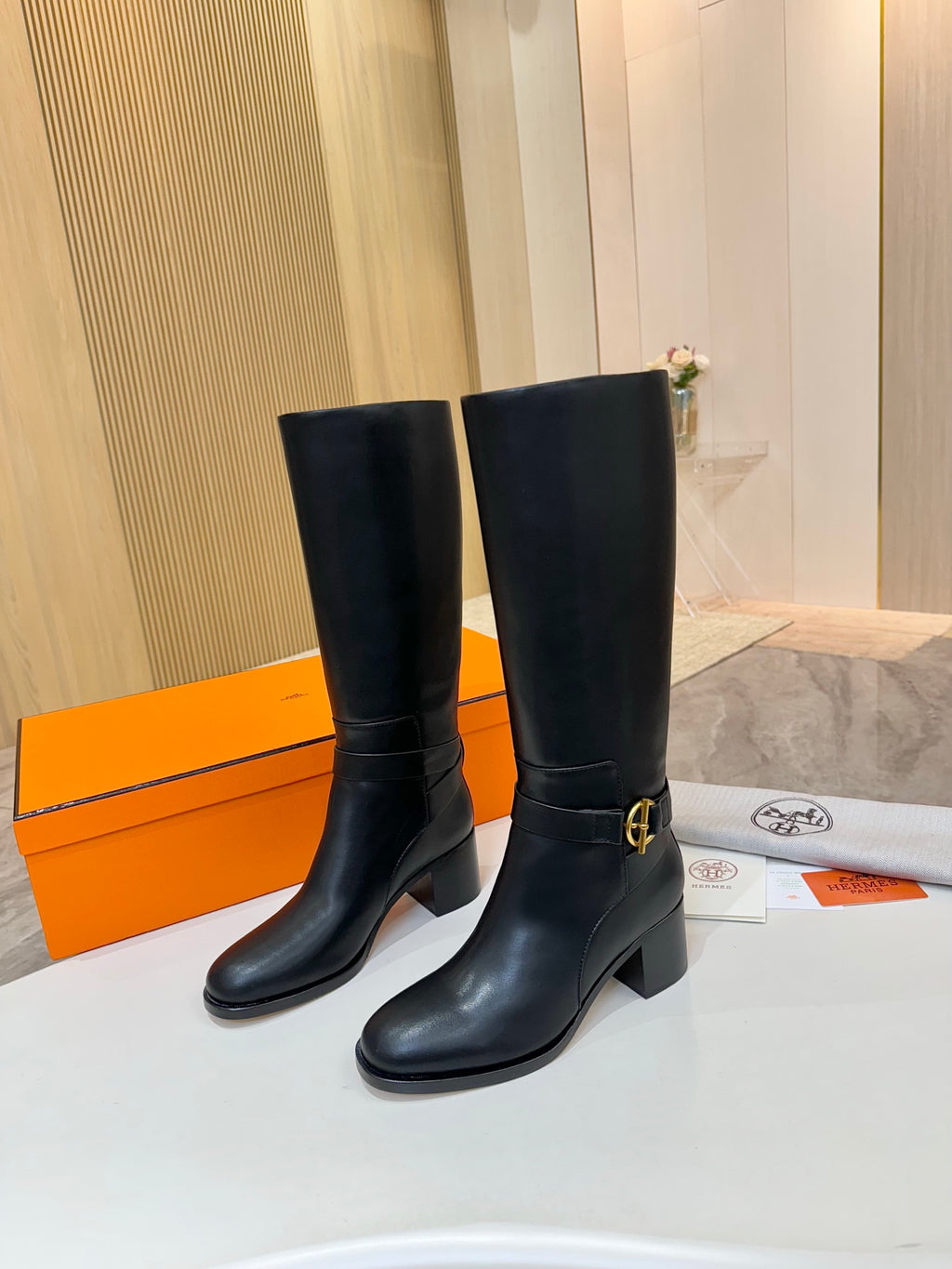 Black leather mid-calf boots with gold logo buckle and stacked block heel