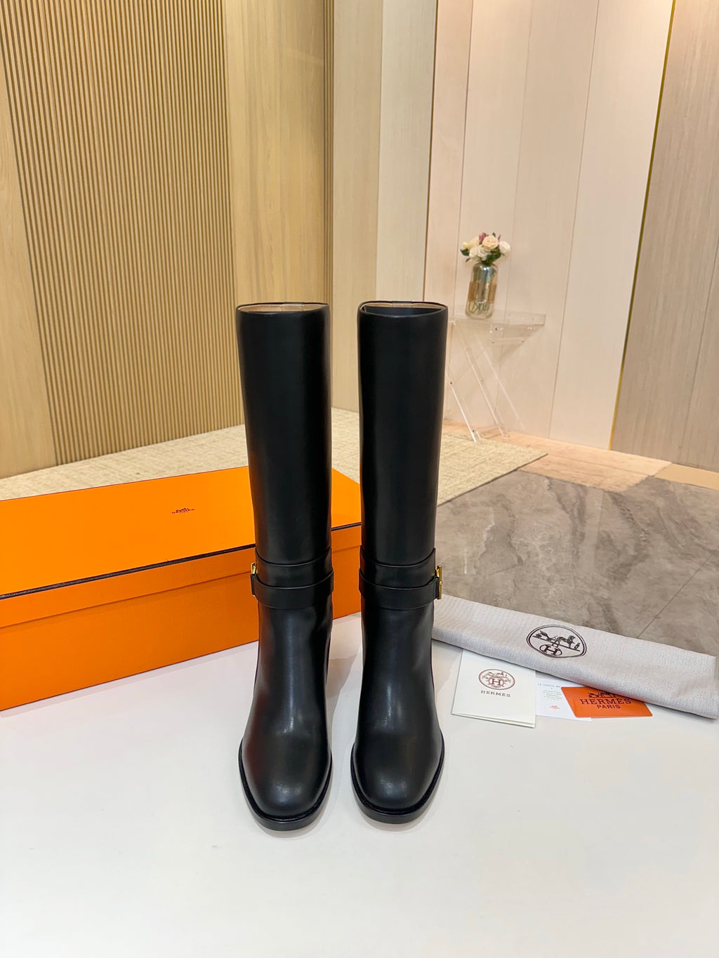 Black leather mid-calf boots standing side by side, gold logo detail