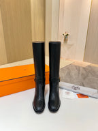 Black leather mid-calf boots standing side by side, gold logo detail