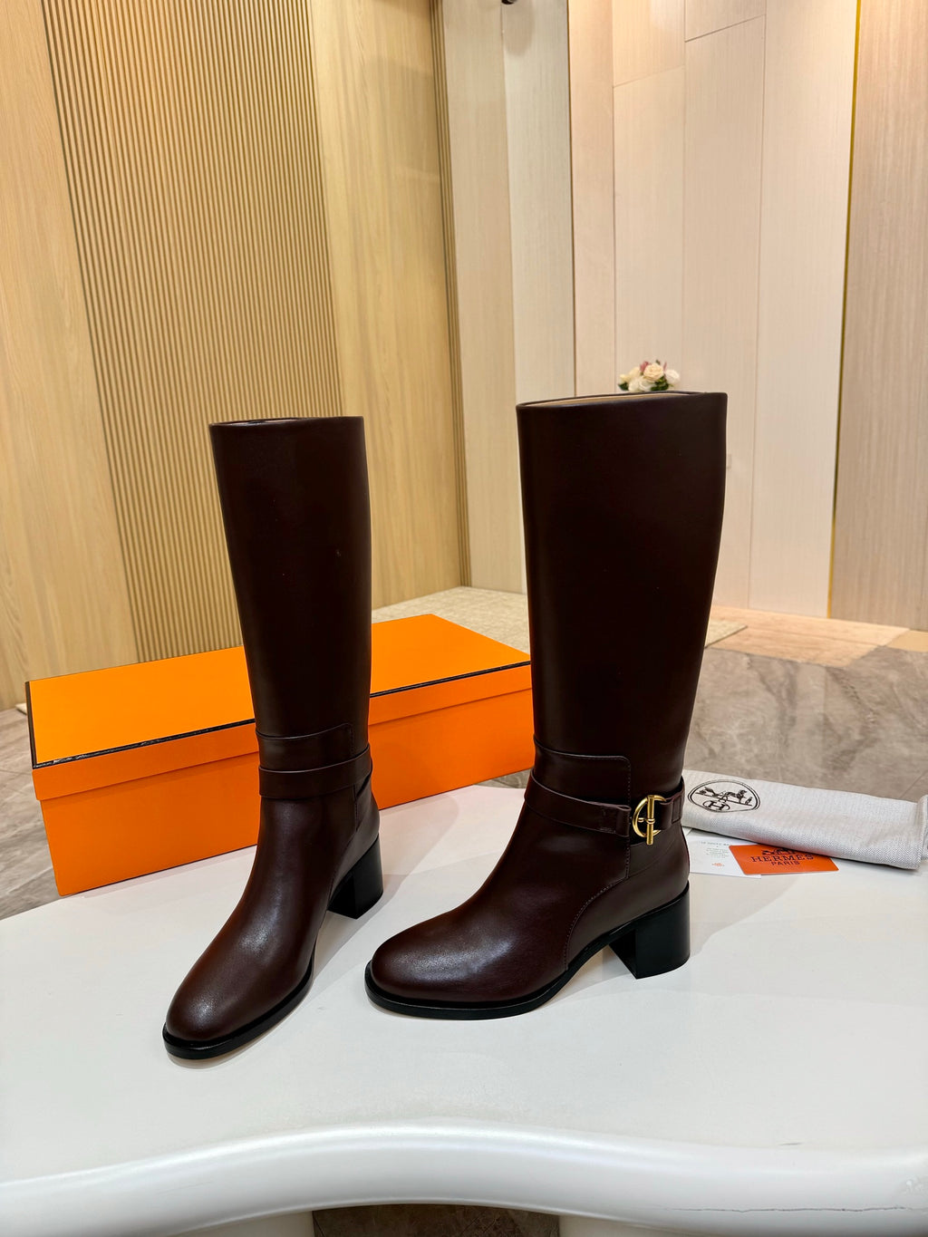 Women's dark brown tall leather boots, front view with gold-tone buckle strap