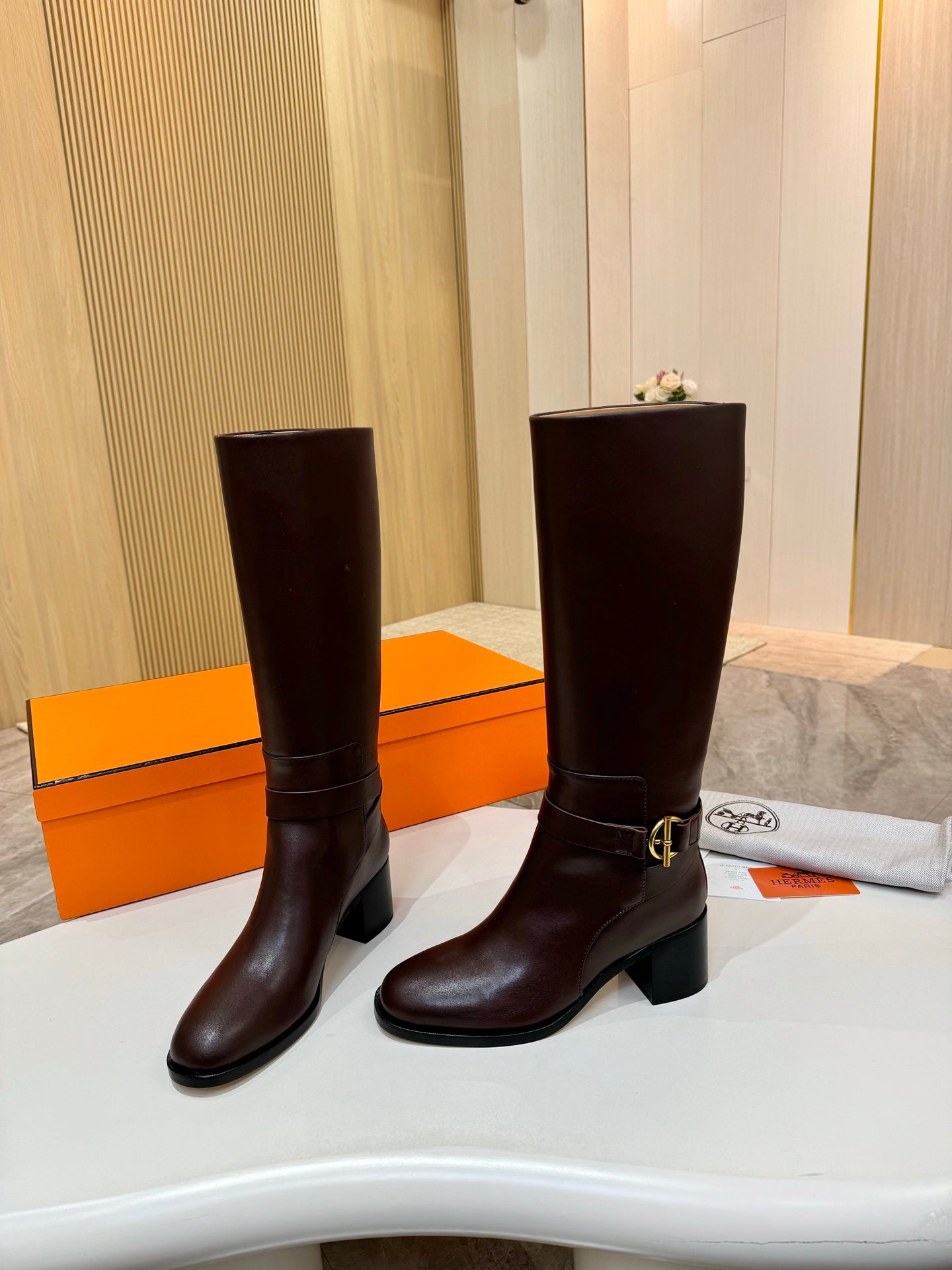 Women's dark brown tall leather boots, front view with gold-tone buckle strap