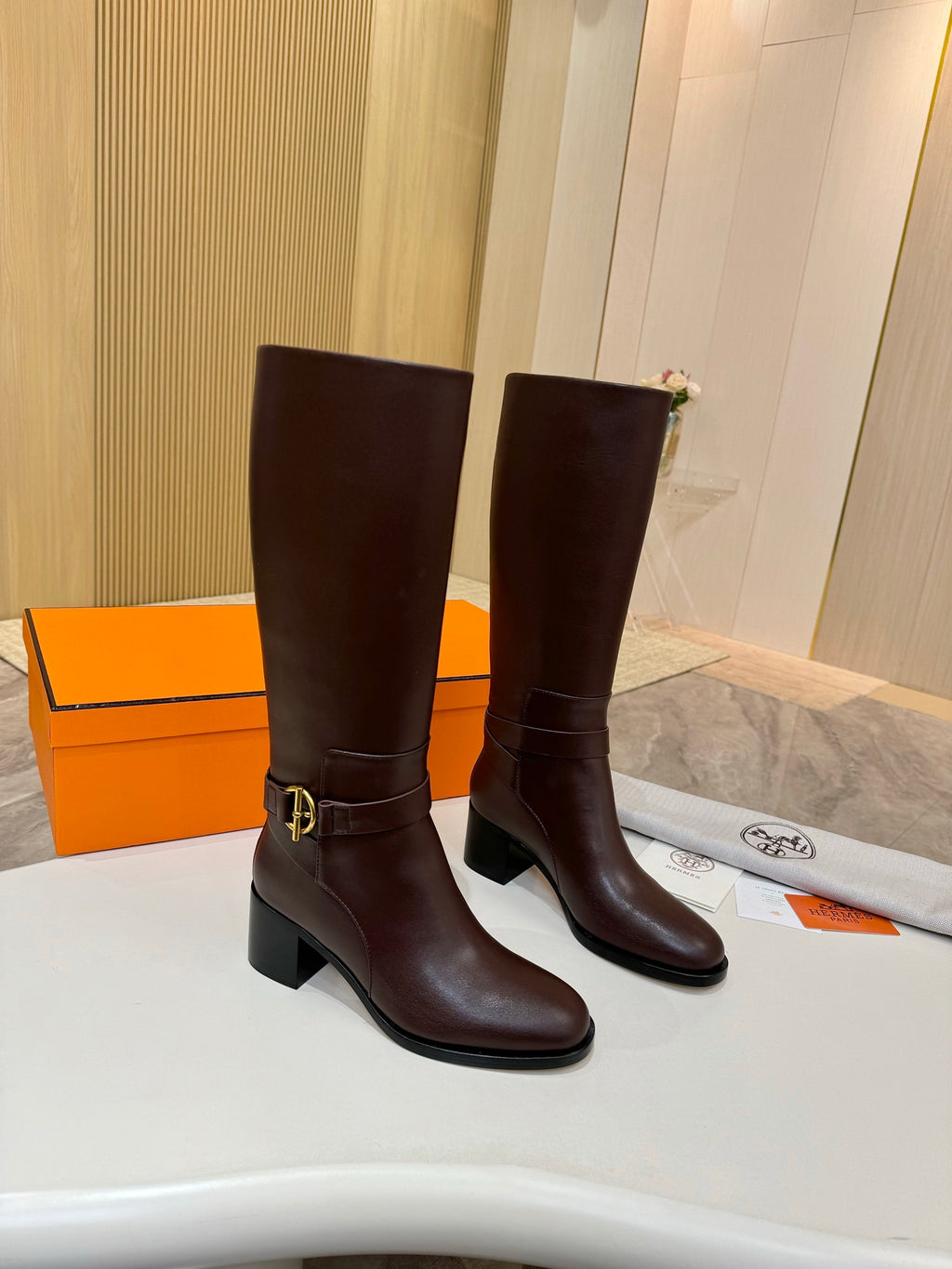 Women's dark brown tall leather boots, front view with gold-tone buckle strap