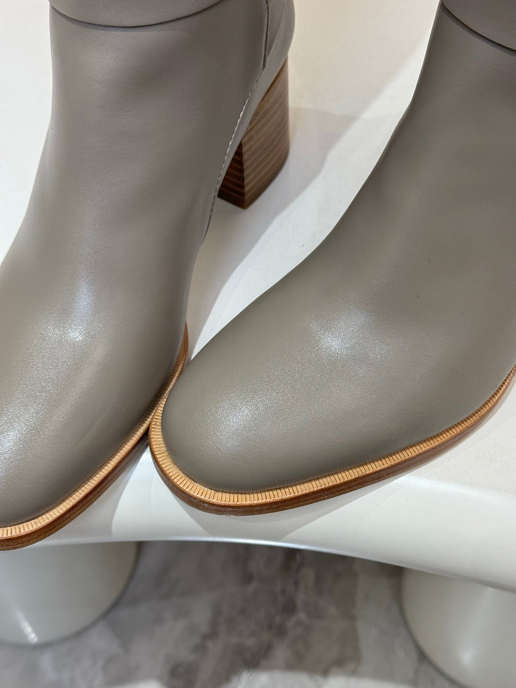 Close-up of women’s gray knee-high leather boots with textured sole and heel
