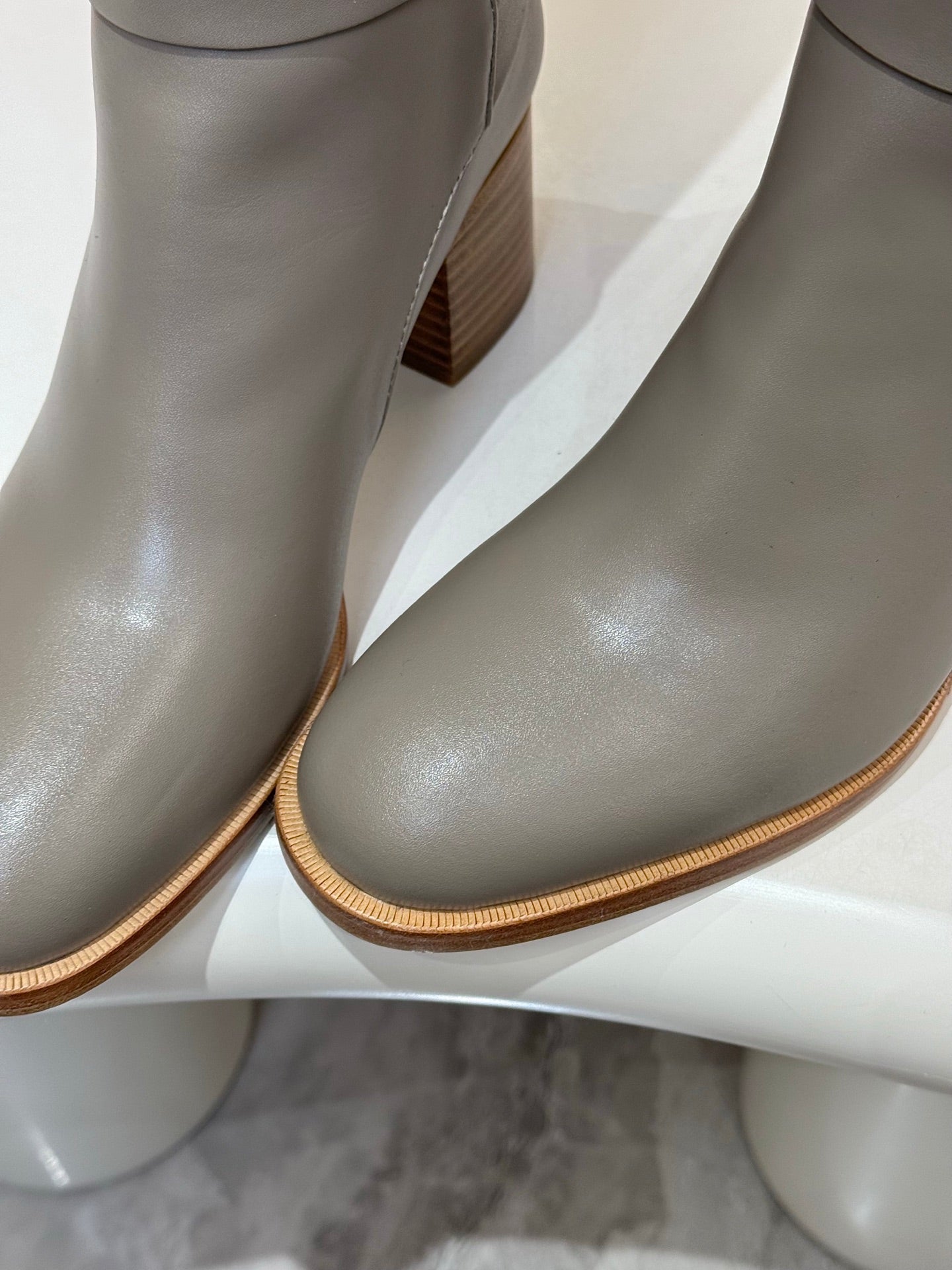 Close-up of women’s gray knee-high leather boots with textured sole and heel