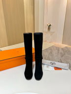 Pair of black suede knee-high boots with gold buckle hardware and block heels