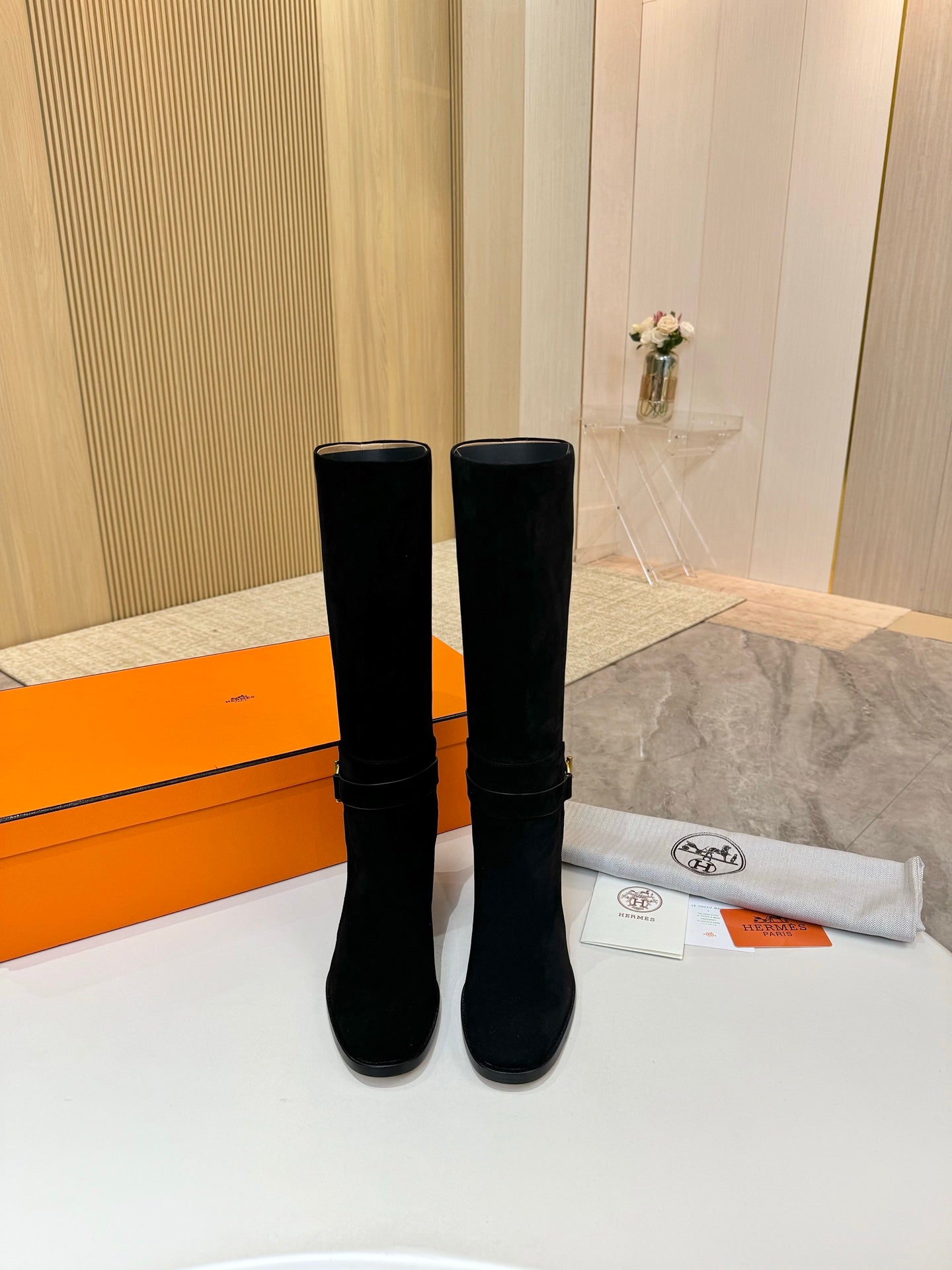 Pair of black suede knee-high boots with gold buckle hardware and block heels