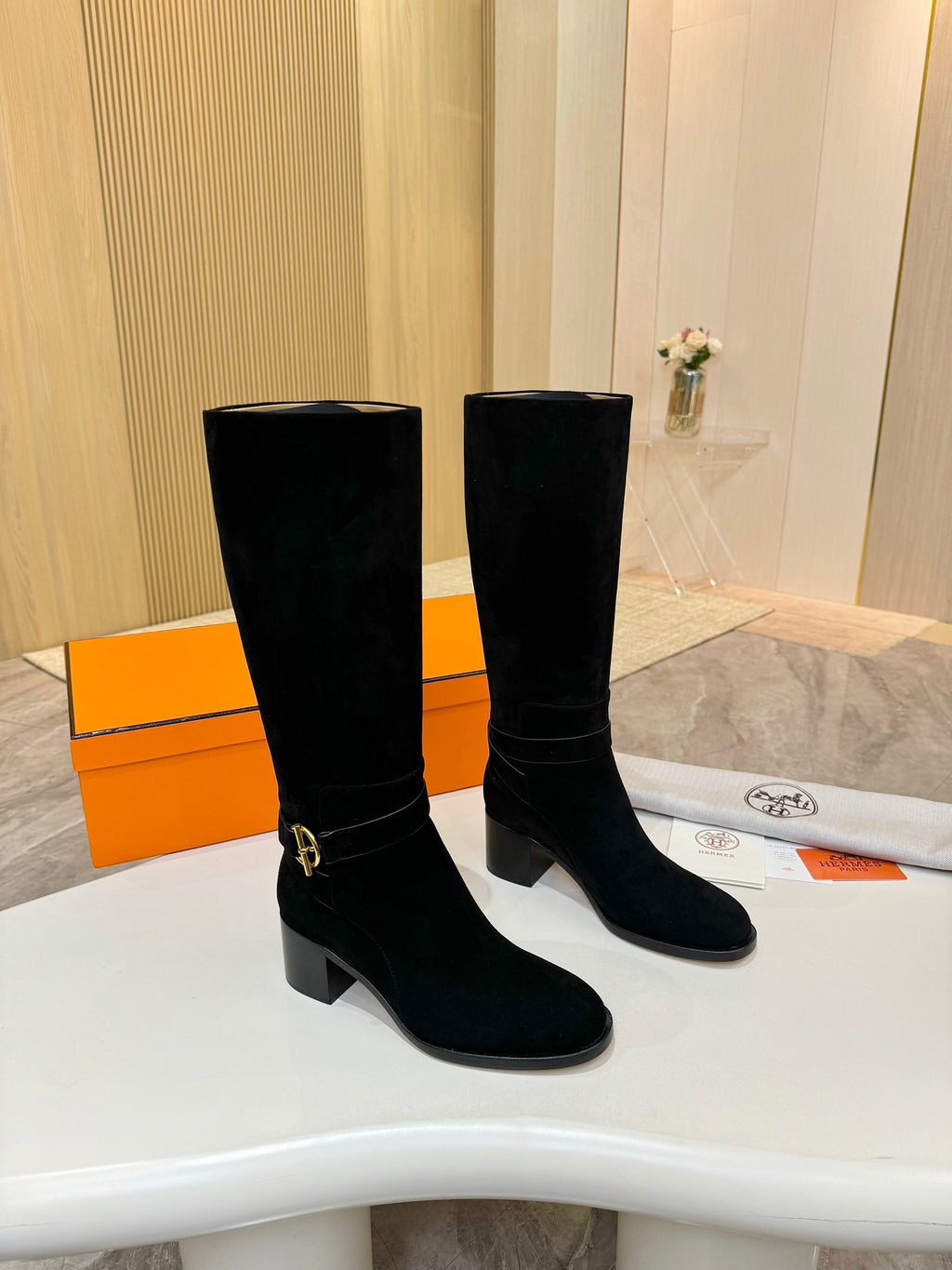 Black suede knee-high boots with gold buckle detail and mid-height block heel