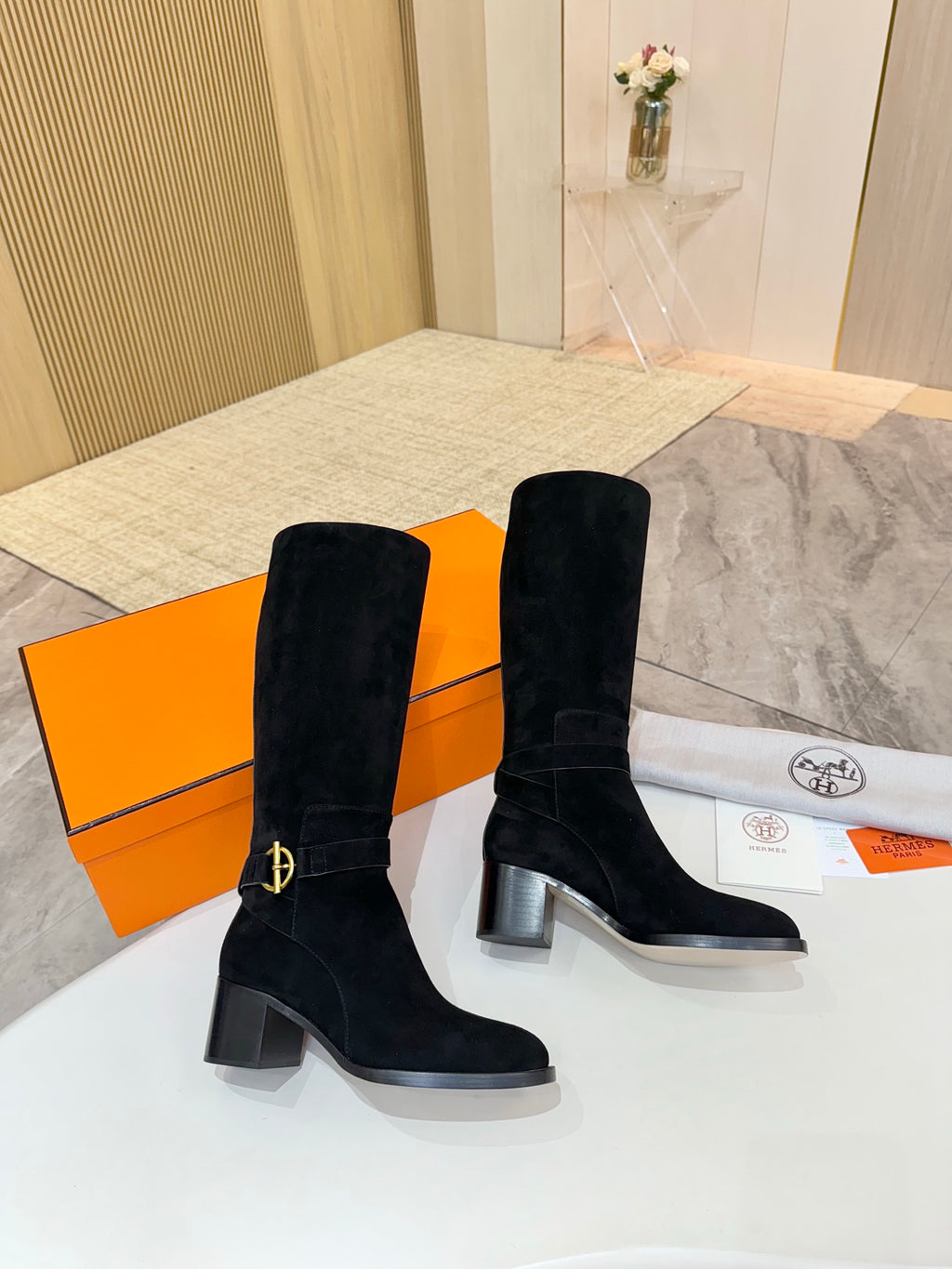 Black suede knee-high boots with gold buckle strap detail and block heel