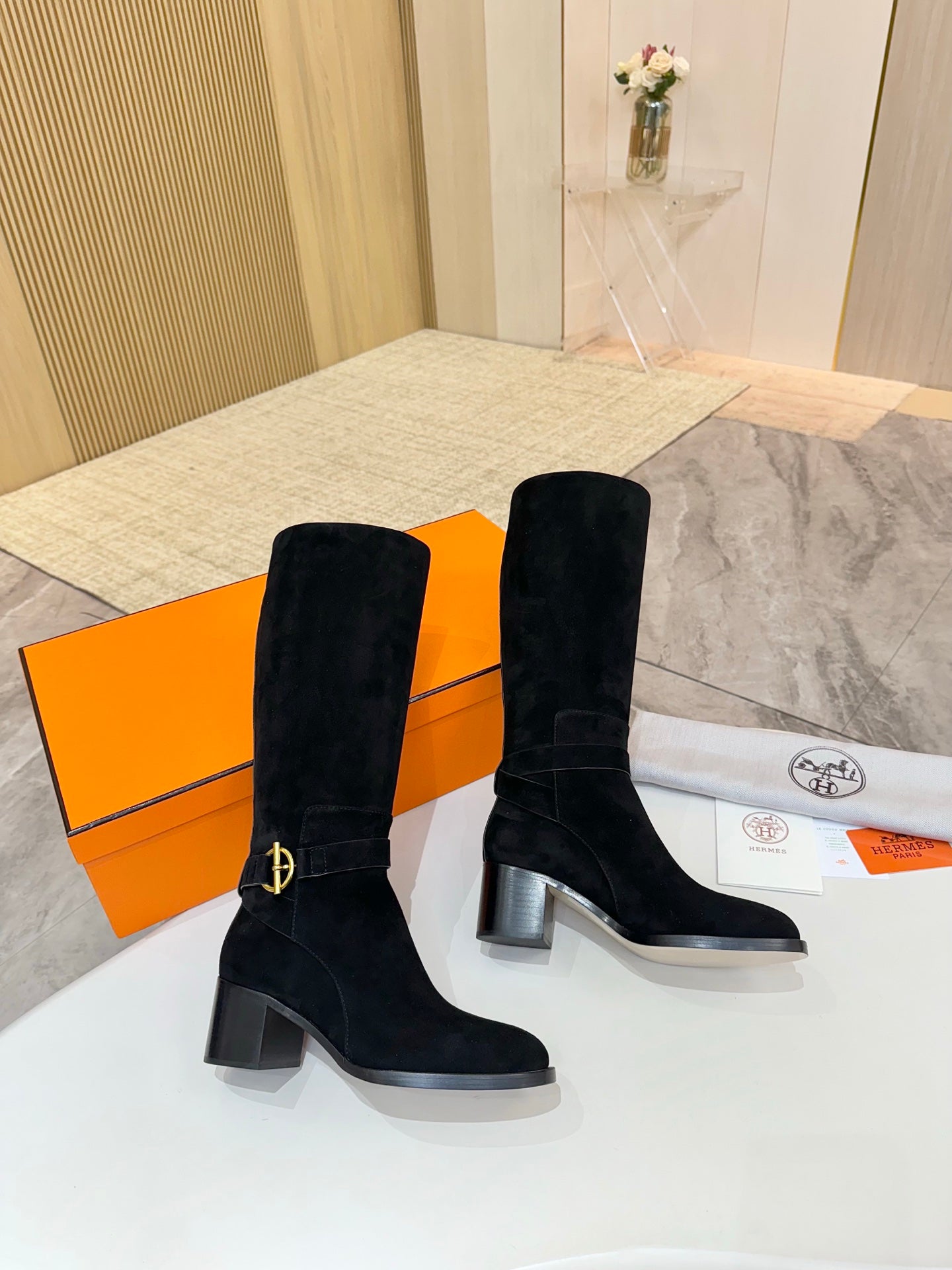 Black suede knee-high boots with gold buckle strap detail and block heel