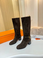 Dark suede knee-high boots standing side-by-side, chunky block heel, buckle strap