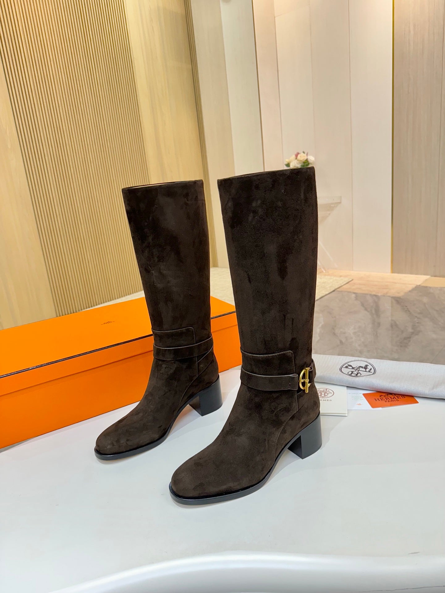 Dark suede knee-high boots standing side-by-side, chunky block heel, buckle strap