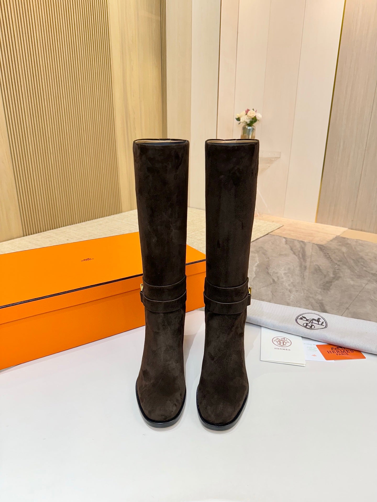 Pair of dark suede knee-high boots with gold-tone buckle strap and heel