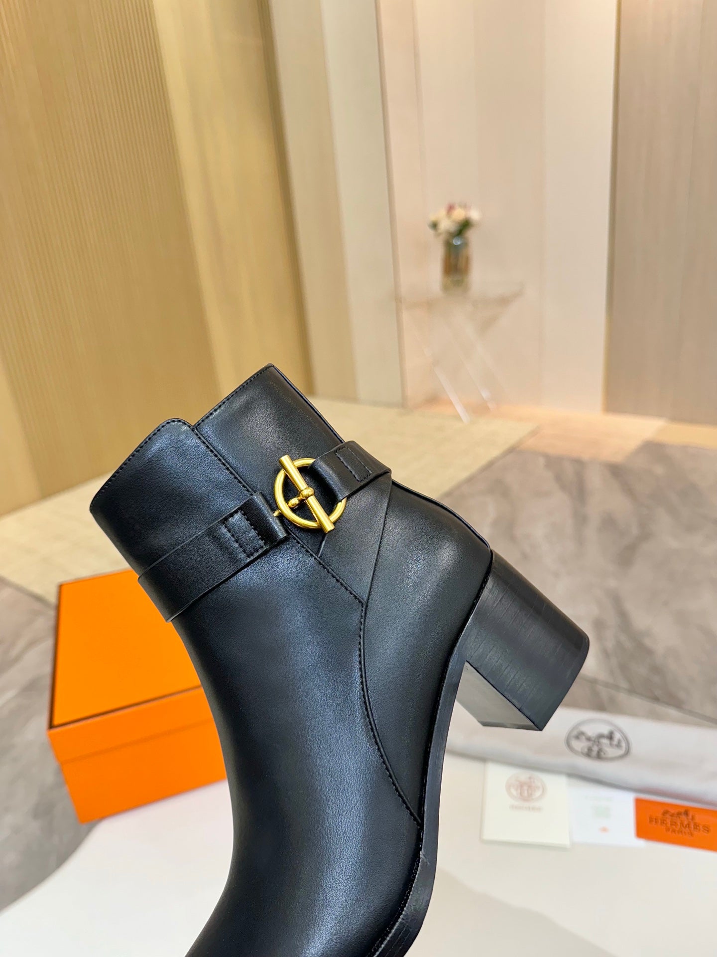 Black leather ankle boots with gold buckle logo strap and mid-height block heel
