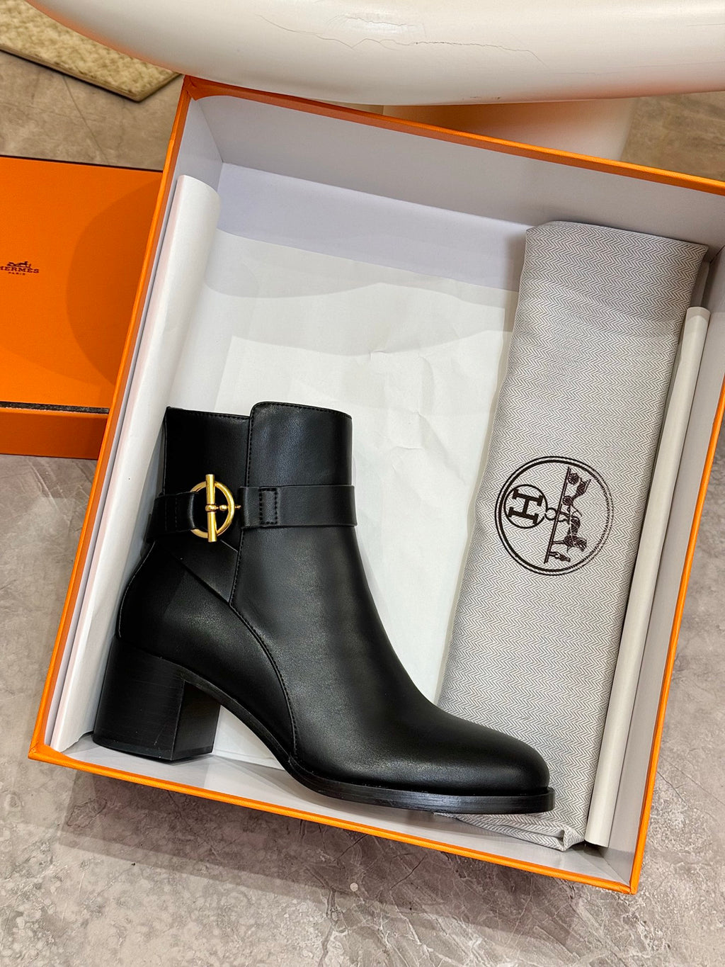 Black leather ankle boot in orange box with gold logo buckle detail