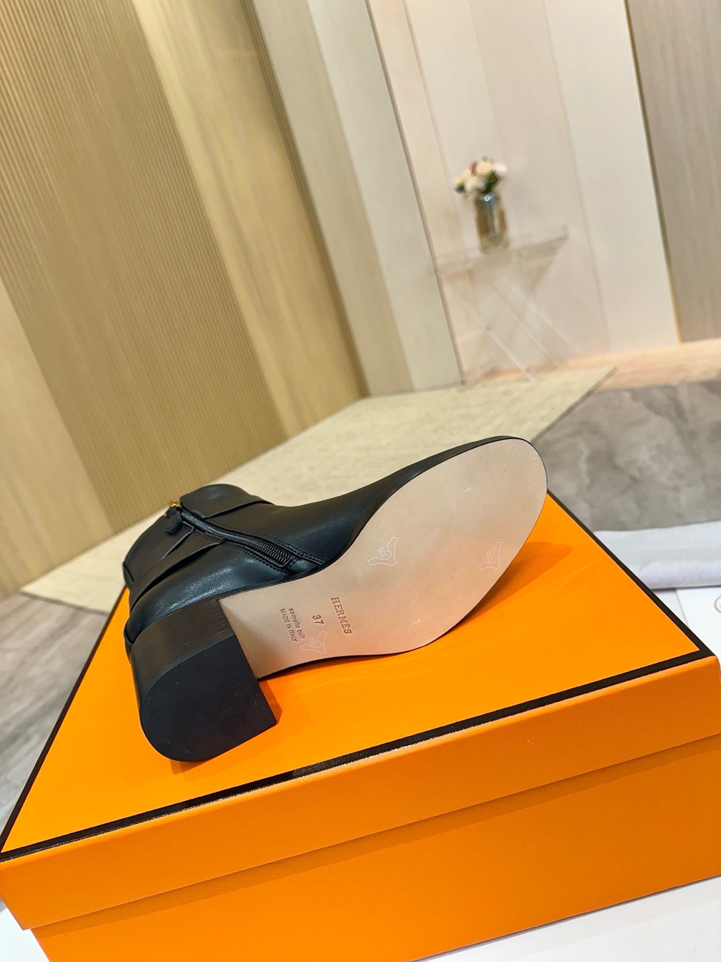 Black leather ankle boot sole view on orange shoebox