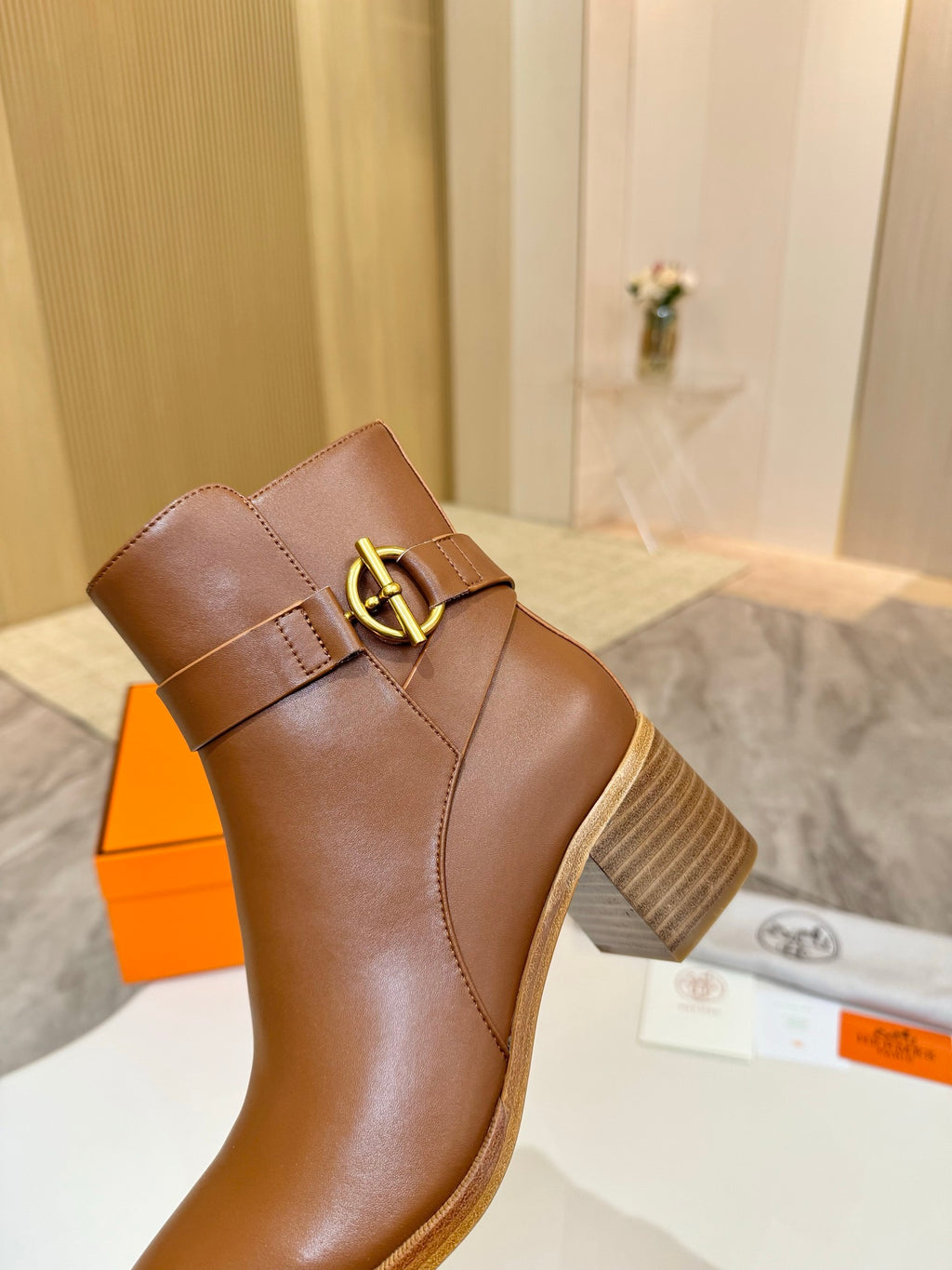Brown leather ankle boot with gold buckle detail on side, close-up