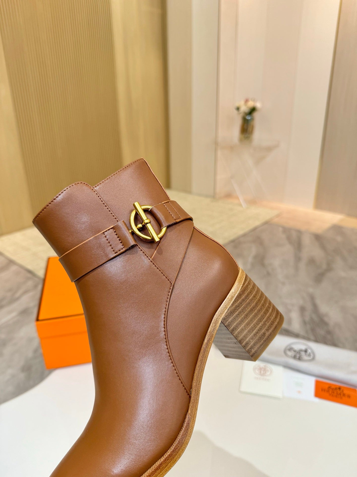 Brown leather ankle boot with gold buckle detail on side, close-up