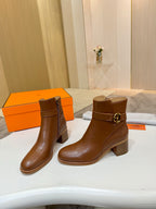 Brown leather ankle boots with gold buckle and stacked block heel, angled view