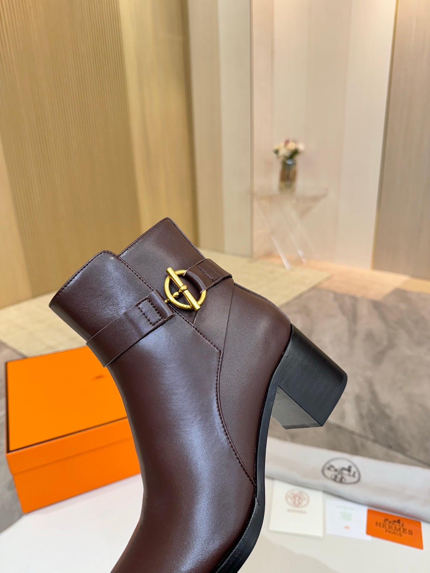 Brown leather ankle boot with gold buckle logo detail on strap